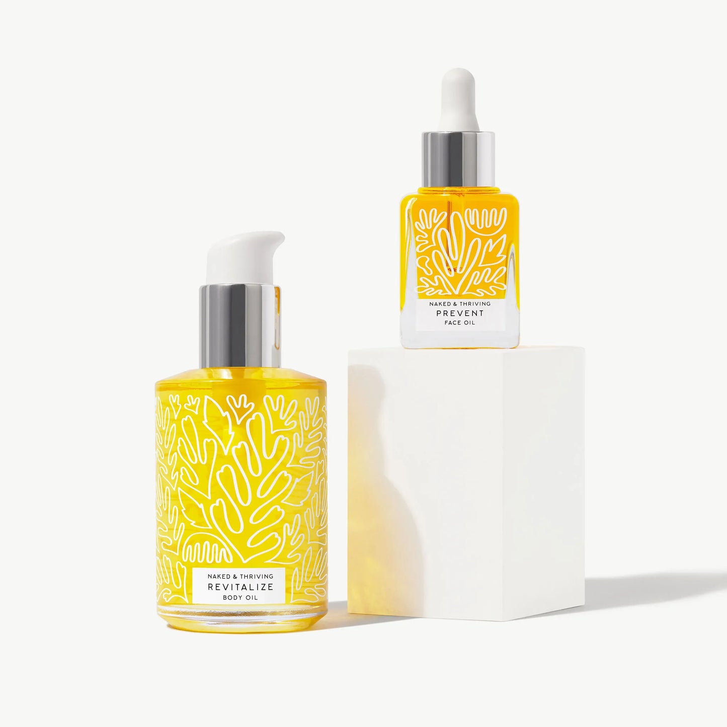 Prevent face oil and Revitalize body oil bottles arranged on a light background