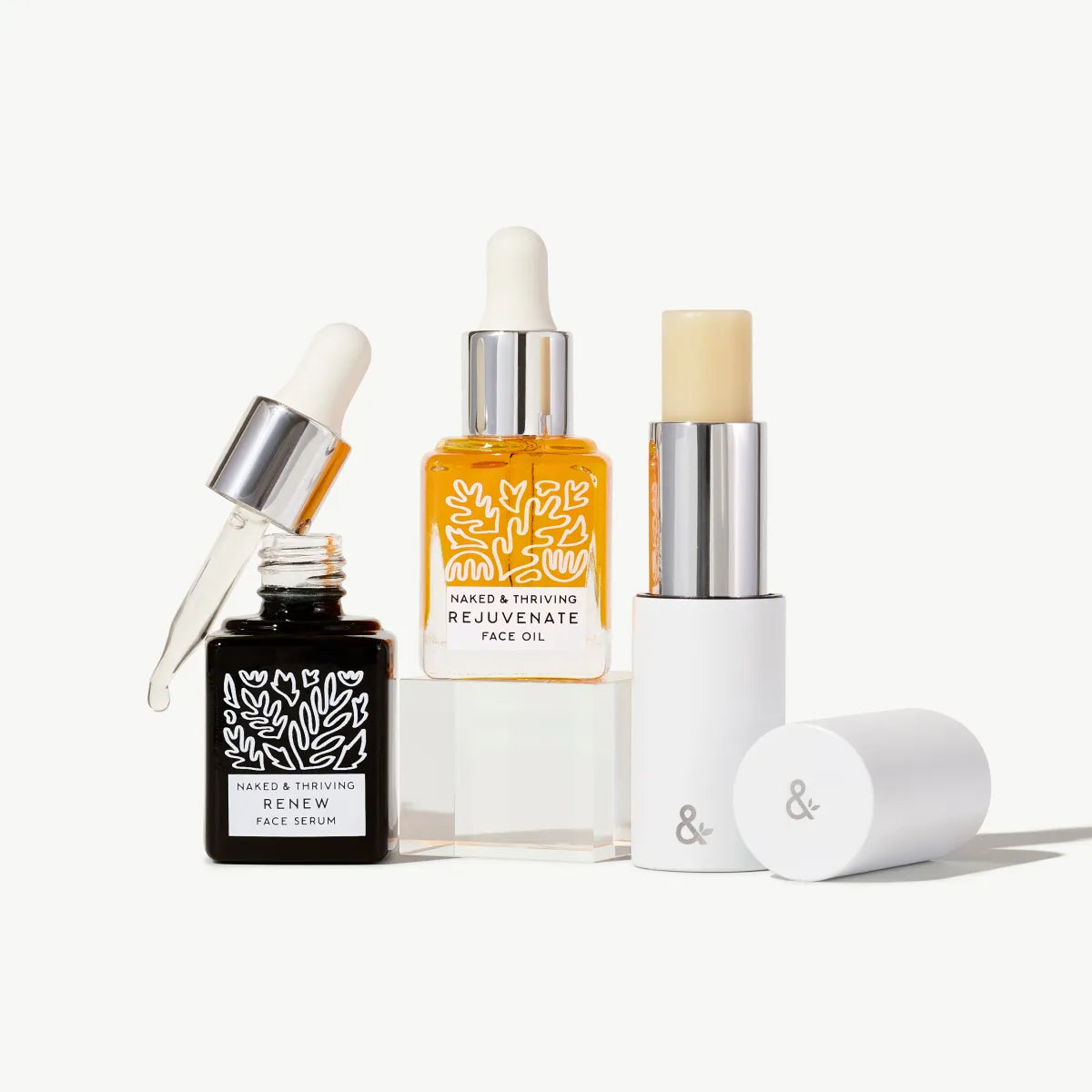 Mini Renew Serum, Mini Rejuvenate Face Oil, and HydraTint Naked Multistick on white background