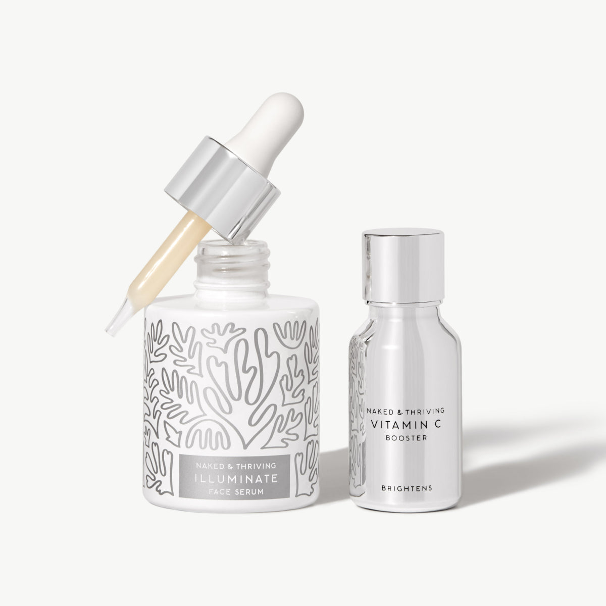 Naked & Thriving Super Bright Set with a patterned dropper bottle of Illuminate BC+ Brightening Serum and a silver bottle of Vitamin C Booster